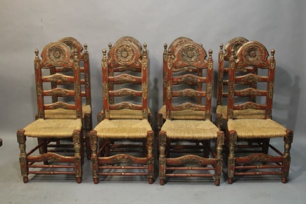 Eight ornate wooden chairs with woven seats.
