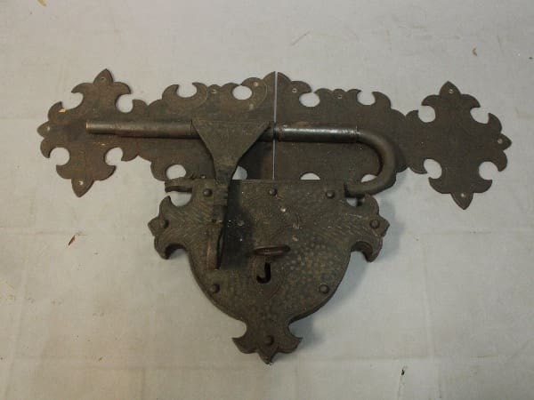 Ornate antique metal latch on display table.