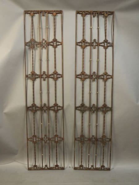 Two ornate metal window grills, vertically aligned.