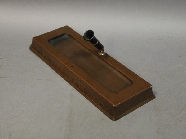 Bronze-colored rectangular object with small pipe.