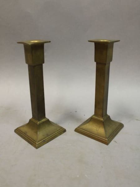 Two brass candlesticks on a gray background.