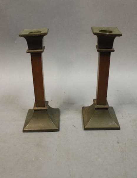 Two vintage metal candlesticks on display.