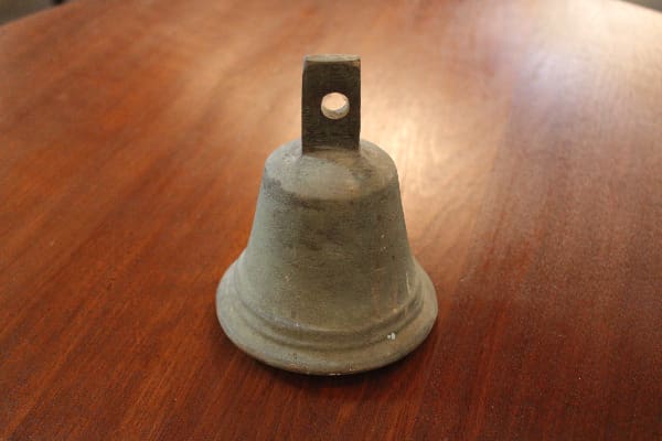 Small metal bell on wooden table.