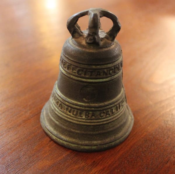 Small bronze bell on wooden surface.