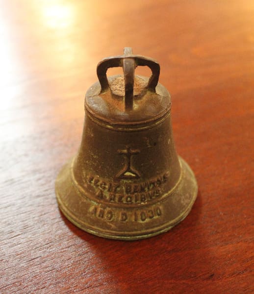 Bronze bell with engraved text on table.