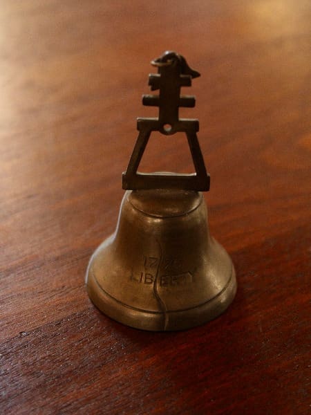 Small metal bell on wooden surface.