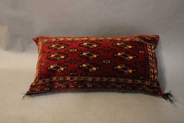 Red patterned decorative pillow on gray background.