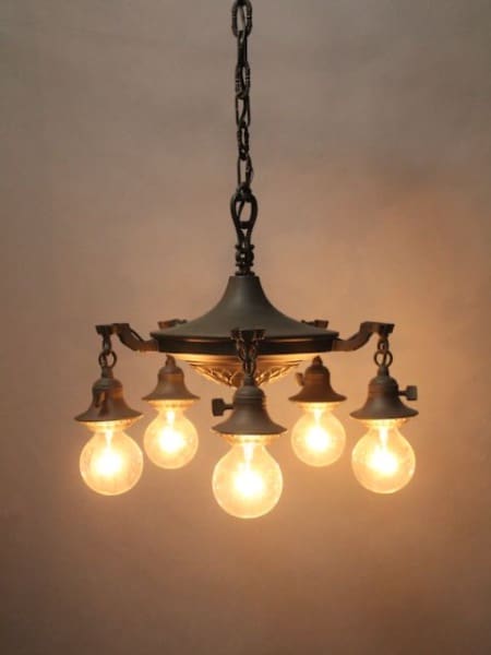 Vintage chandelier with five glowing bulbs.