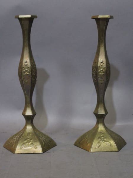 Two ornate brass candlesticks on display.