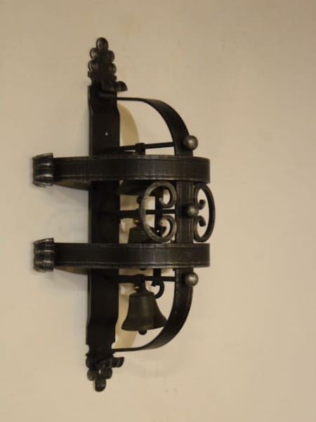 Ornate black metal wall-mounted bell fixture.