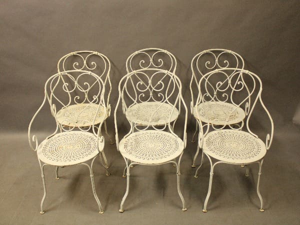Six ornate white wrought iron chairs.