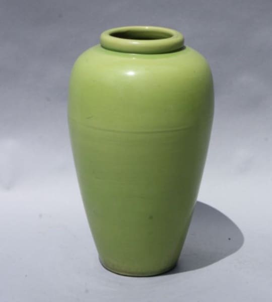 Green ceramic vase on gray background.