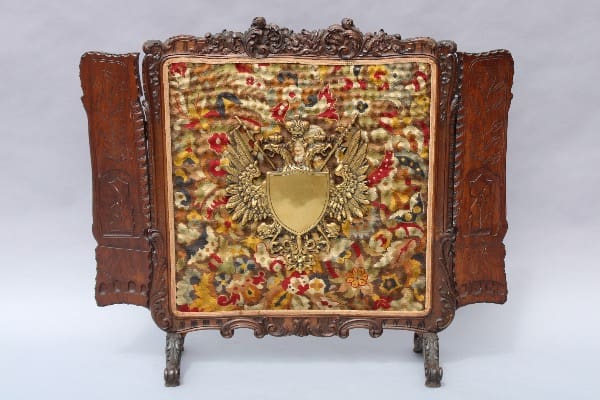 Ornate wooden screen with colorful embroidered panel.
