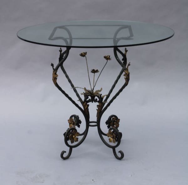 Glass table with ornate wrought iron base.