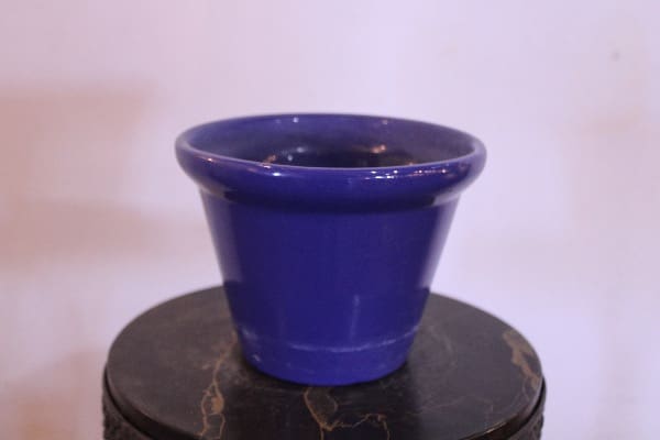 Blue ceramic pot on circular stand.