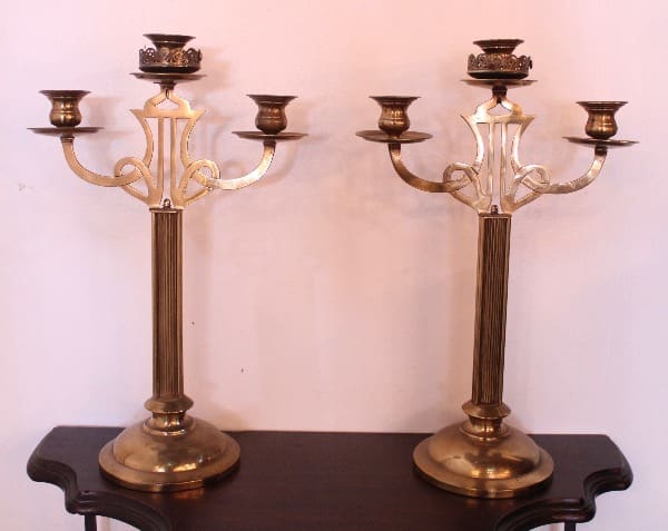 Two antique brass candelabras on table.