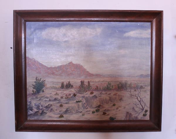 Painting of a desert landscape in frame.