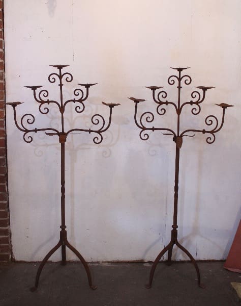 Two ornate metal candelabra stands displayed indoors.