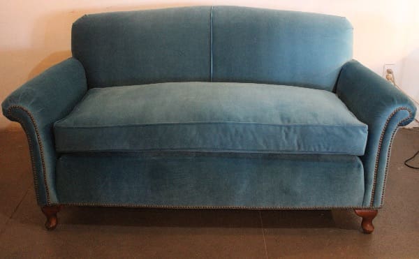 Blue upholstered two-seater sofa with wooden legs.