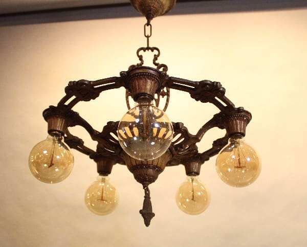 Vintage chandelier with five glowing bulbs.