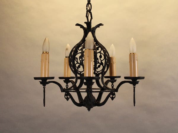Ornate black chandelier with five candles.