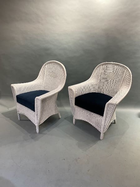 Two white wicker chairs with navy cushions.