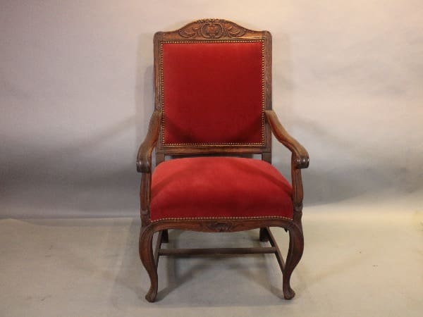Ornate wooden chair with red upholstery.