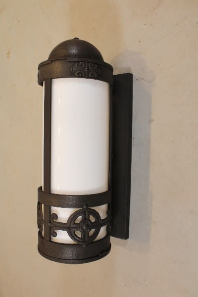 Ornate wall-mounted cylindrical light fixture.