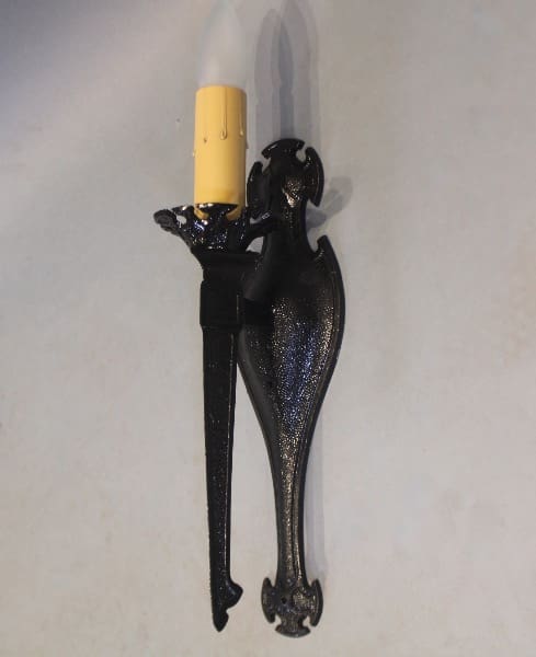 Black ornate wall sconce with candle.