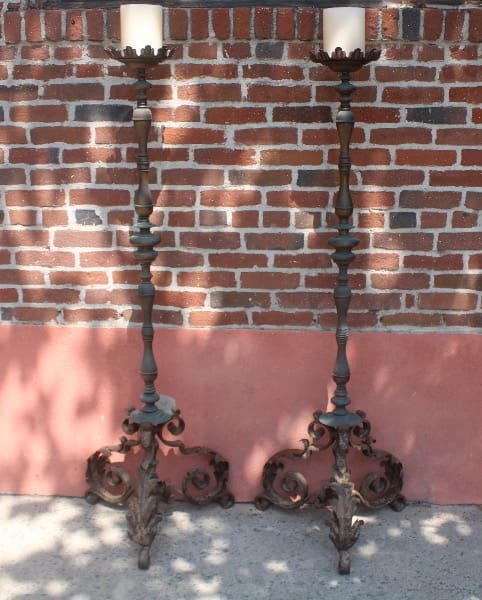 Two ornate candle holders against brick wall.