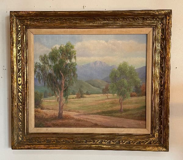 Framed landscape painting with trees and mountains.
