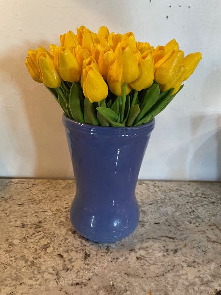 Yellow tulips in a blue ceramic vase.