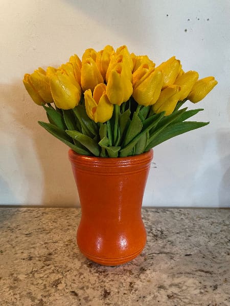 Yellow tulips in an orange vase.