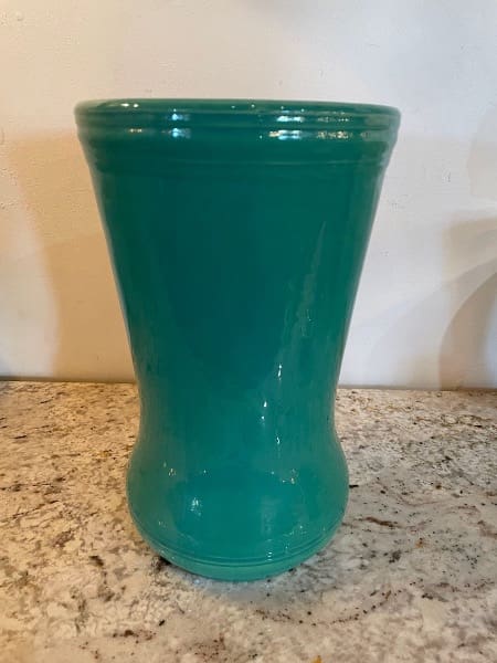 Green ceramic vase on granite countertop.