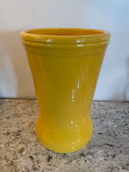 Yellow ceramic vase on speckled countertop.