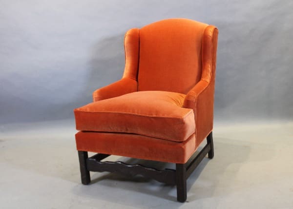 Orange upholstered armchair with wooden legs.