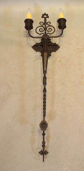Ornate wall sconce with two lit candles.