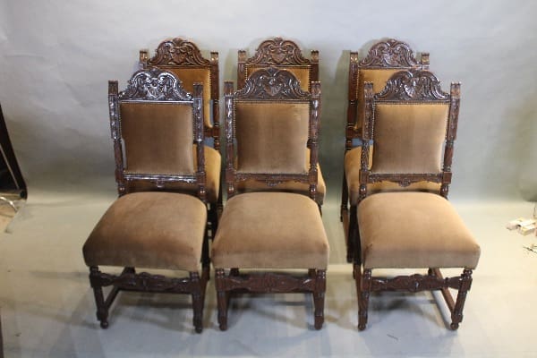 Six ornate wooden chairs with upholstered seats.