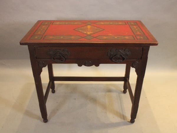 Antique wooden table with ornate red top.
