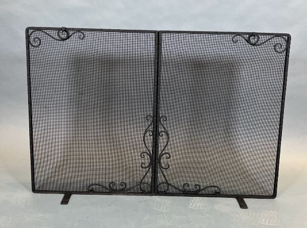 Decorative black metal fireplace screen with mesh.