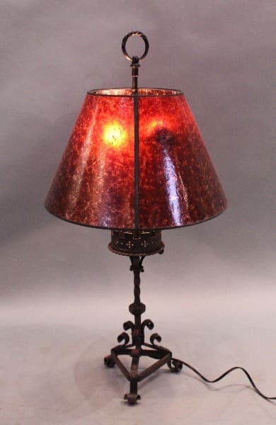 Red lampshade on ornate metal base.