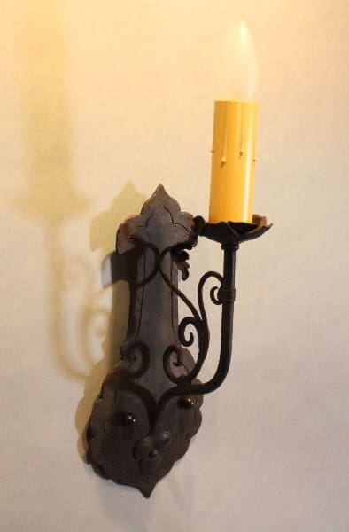 Ornate wall sconce with lit candle.