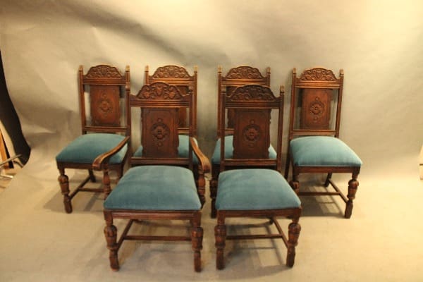 Six ornate wooden chairs with blue cushions.