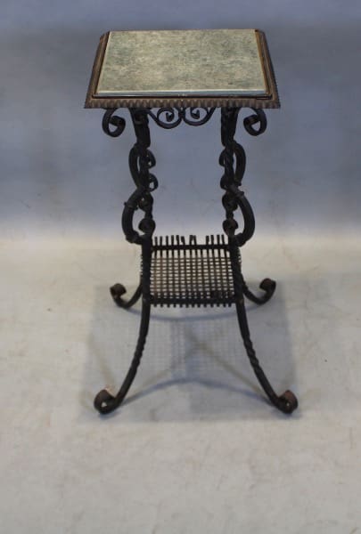 Ornate metal plant stand with square top.
