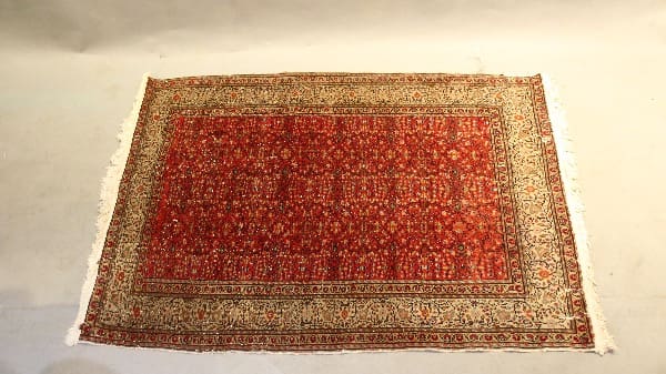 Red patterned oriental rug on light floor.