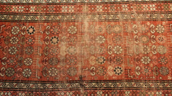 Worn, vintage carpet with floral patterns.