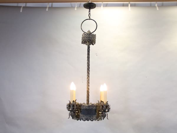 Antique metal chandelier with lit candles.