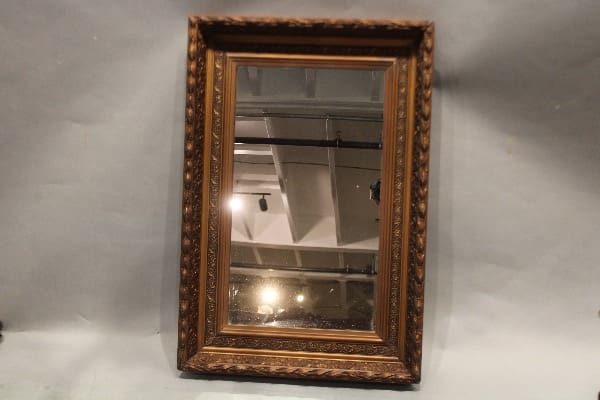 Ornate framed mirror reflecting ceiling lights.