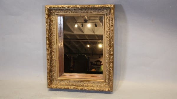 Ornate gold-framed mirror on plain wall.