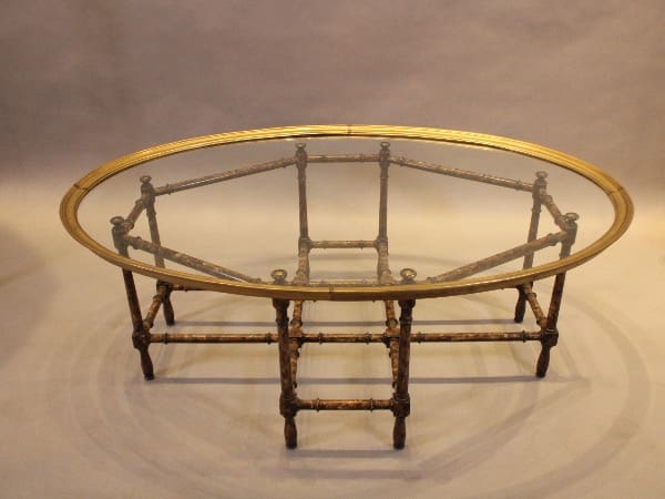 Oval glass table with decorative metal frame.